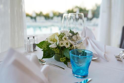 a table with a wine glass and a vase of flowers at Jesolopalace Hotel & Aparthotel in Lido di Jesolo