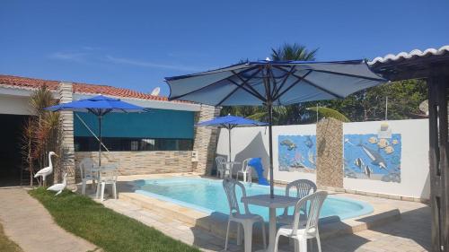 a pool with a table and chairs and an umbrella at CASA TEMPORADA SÃO JOSE DA COROA GRANDE - PE in São José da Coroa Grande