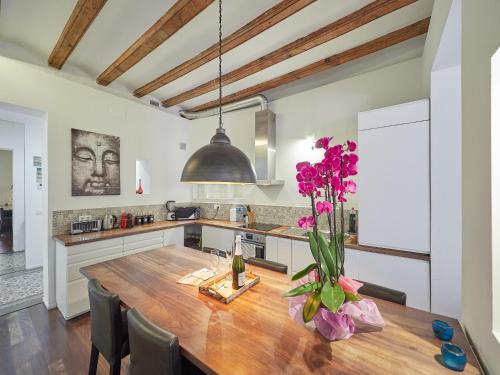 a kitchen with a wooden table with purple flowers on it at Barcelonaforrent Alessandra Central Ramblas Apartment in Barcelona