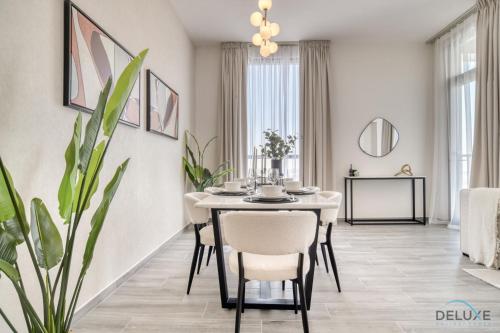 a dining room with a table and a plant at Pleasant 2BR with Assistant Room at Mesk 1 Midtown Dubai Production City by Deluxe Holiday Homes in Dubai