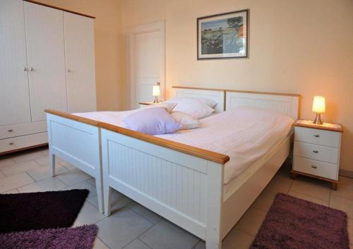 ein Schlafzimmer mit einem großen weißen Bett mit zwei Lampen in der Unterkunft Haasehof in Sittensen
