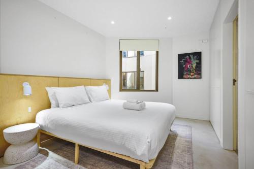 een slaapkamer met een groot wit bed en een raam bij Bourke Street Urban Retreat in Melbourne