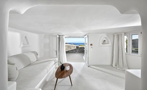 a white living room with a white couch and a table at VLIA Mykonos in Kalafatis