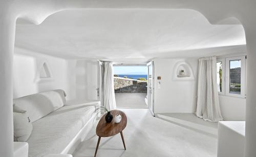 ein weißes Wohnzimmer mit einem weißen Sofa und einem Tisch in der Unterkunft VLIA Mykonos in Kalafatis