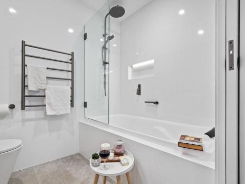 a white bathroom with a toilet and a table at Luxury 5 Bedroom Home - Sentinel Chalet - Snowy Mountains - Jindabyne in Jindabyne