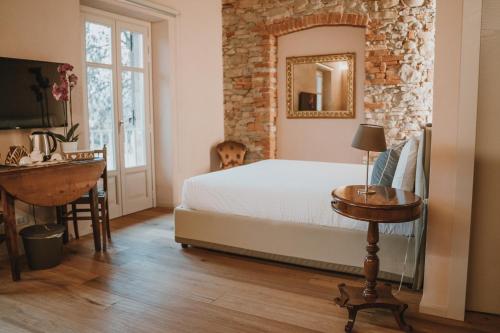 Schlafzimmer mit einem Bett, einem Tisch und einem Spiegel in der Unterkunft LA CASCINA DI CARLOTTA 1846 agriturismo in Alba