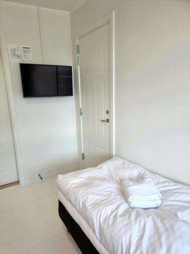 a white room with a bed and a flat screen tv at Skovsgård Hotel in Brovst