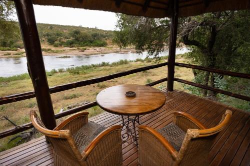 a table and chairs on a porch with a view of a river at Nyati Safari Lodge in Hoedspruit