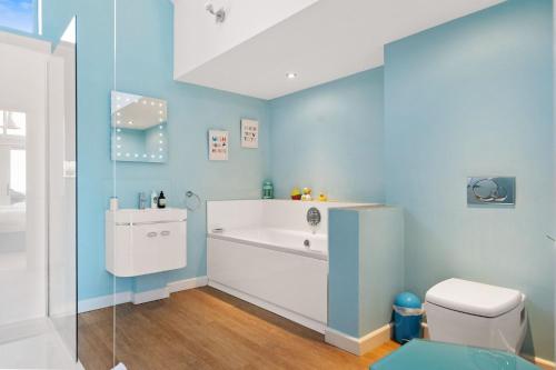 een blauwe badkamer met een bad en een toilet bij The Looking Glass in Dartmouth
