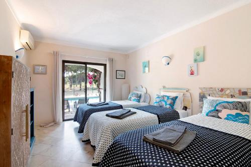 um quarto com 3 camas com lençóis azuis e brancos em Casa Quarenta Garrão na Quinta do Lago