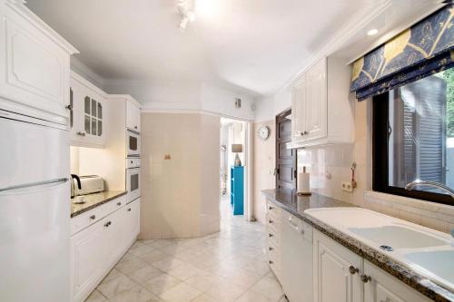 uma cozinha com armários brancos, um lavatório e uma janela em Casa Quarenta Garrão na Quinta do Lago