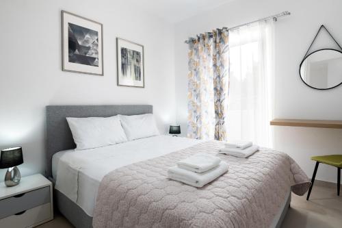una camera da letto con un letto bianco e asciugamani di ILIADA Luxury Apartment a Porto Rafti