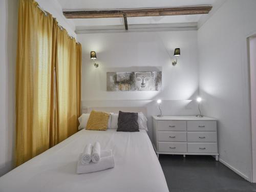 une chambre avec un lit blanc avec deux serviettes dessus dans l'établissement BarcelonaForRent Alessandra Central Ramblas, à Barcelone