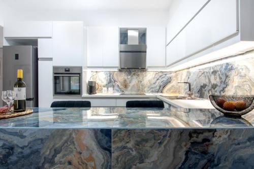una cucina con ripiano in marmo e bottiglia di vino di ILIADA Luxury Apartment a Porto Rafti