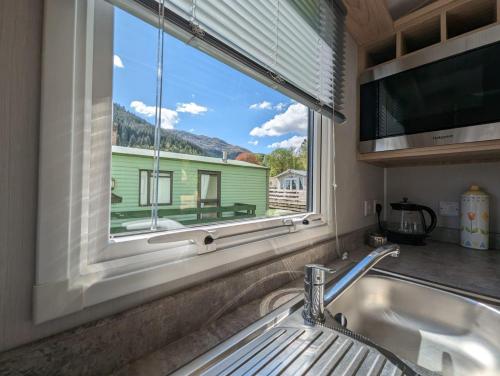 a kitchen with a sink and a window with a house at The Castleton 20 in Ardentinny