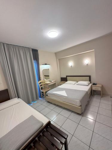 1 dormitorio con 2 camas, mesa y silla en Hotel Afrodite, en Neoi Poroi