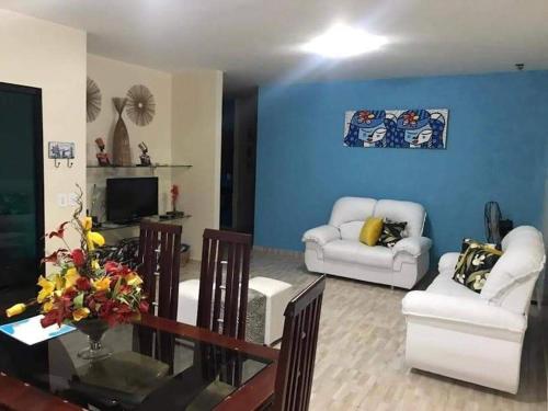 uma sala de estar com mobiliário branco e uma parede azul em CASA TEMPORADA SÃO JOSE DA COROA GRANDE - PE em São José da Coroa Grande