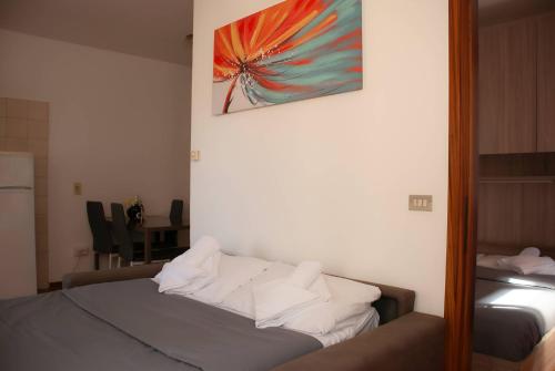 - une chambre dotée d'un lit avec des draps blancs et une peinture murale dans l'établissement 1Dest - Take it Easy, à Riva del Garda