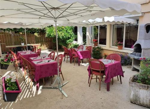 un patio con mesas y sillas bajo una sombrilla en Hôtel Ecu de france, en Secondigny