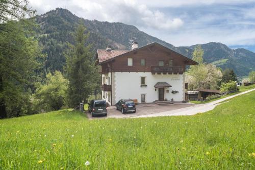 una casa grande con dos coches estacionados frente a ella en Cësa Gravina Suaut, en Ortisei