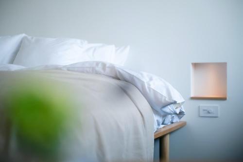a bed with white sheets and pillows on a table at 穴吹邸 / ANABUKI-TEI in Takamatsu