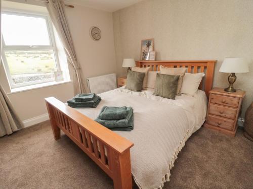 een slaapkamer met een groot bed met twee groene handdoeken erop bij The Hollow in Hexham