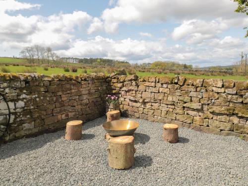 a stone wall with a bowl and some stools at The Hollow in Hexham