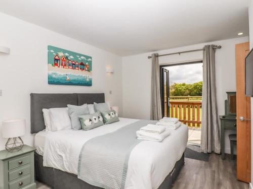 a bedroom with a large bed and a balcony at Strawberry Bank - Kingfisher in Holsworthy