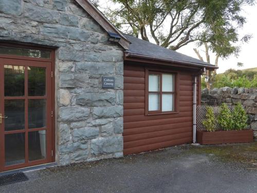 a cabin with a door and a stone building at Nature's Oasis: Pet-Friendly Snowdonia Cottage in Trawsfynydd