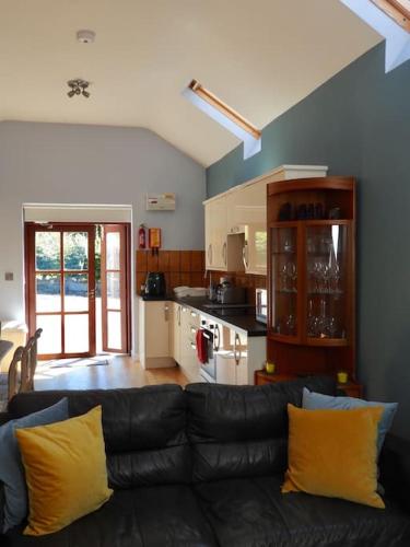 a living room with a black couch and a kitchen at Nature's Oasis: Pet-Friendly Snowdonia Cottage in Trawsfynydd