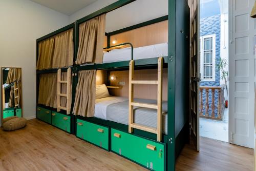 マラガにあるThe Urban Jungle Hostelの緑色の二段ベッド1台、二段ベッド2台が備わる客室です。