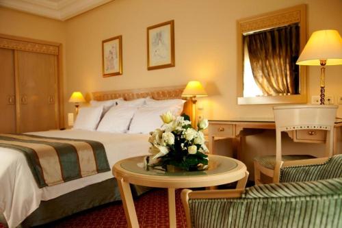 a hotel room with a bed and a table with flowers at Regency Tunis Hotel in Gammarth