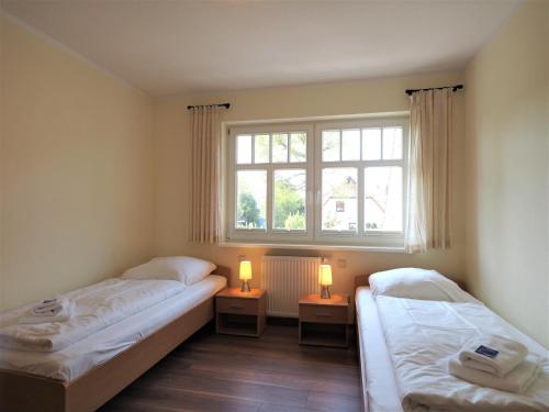 two beds in a room with a window and two lamps at Kinnekulle 2 in Zingst