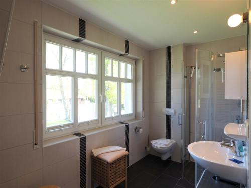 ein Bad mit einem Waschbecken, einem WC und einem Fenster in der Unterkunft Kinnekulle 2 in Zingst