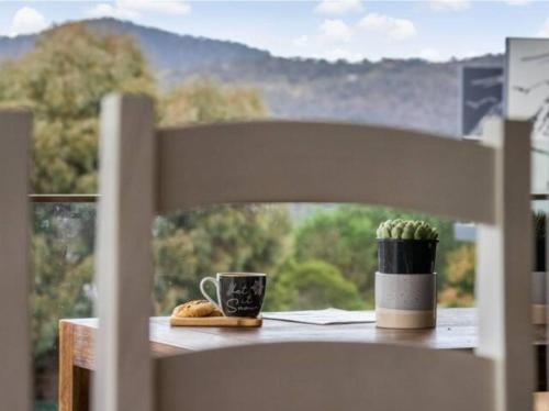 a table with a cup of coffee and a cactus at Luxury 5 Bedroom Home - Sentinel Chalet - Snowy Mountains - Jindabyne in Jindabyne