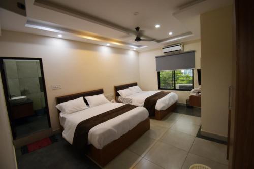 um quarto de hotel com duas camas e uma janela em ARAKKAL GUESTHOUSE em Kalpetta