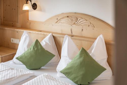 a bed with white and green pillows on it at Residence Diana Apartment 301 in Terento