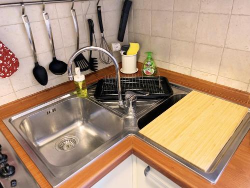 a stainless steel sink in a kitchen with a cutting board at Casa di Arianna in centro storico a Vimercate in Vimercate