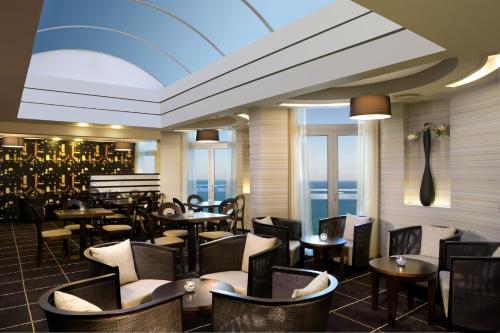 a restaurant with tables and chairs with a view of the ocean at Dan Panorama Tel Aviv Hotel in Tel Aviv