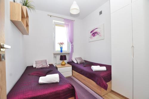 duas camas num pequeno quarto com lençóis roxos em Apartament Chełmiński em Toruń