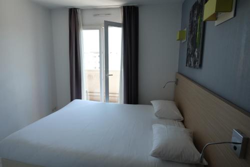une chambre avec un grand lit blanc avec une fenêtre dans l'établissement Palais Des Dômes 718, à Nice