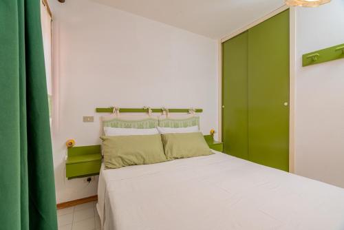 um quarto com uma grande cama branca com cortinas verdes em Rena Bianca House by Wonderful Italy em Olbia