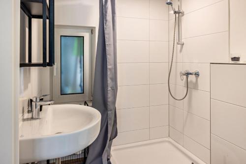 uma casa de banho branca com um lavatório e um chuveiro em Tinyhouse Baumann em Quickborn
