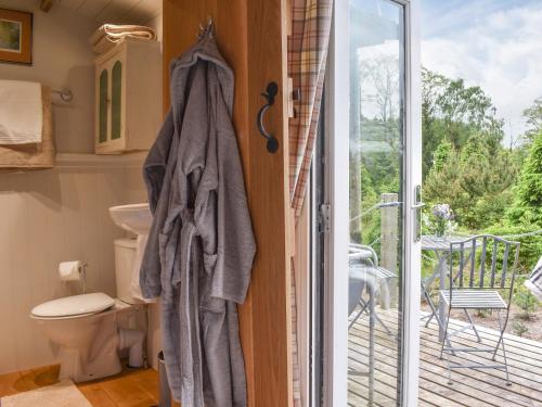 a bathroom with a toilet and a sliding glass door at Spruce Shepherds Hut in Wilmslow