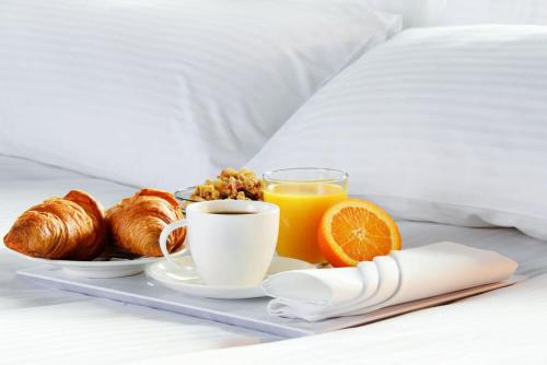 a tray of breakfast foods and orange juice on a bed at Ibiza Plaza Hotel in Anápolis