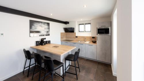 une cuisine avec une table en bois et des chaises noires dans l'établissement Le Ruthénois T2 avec terrasse, classé meublé de tourisme, à Rodez