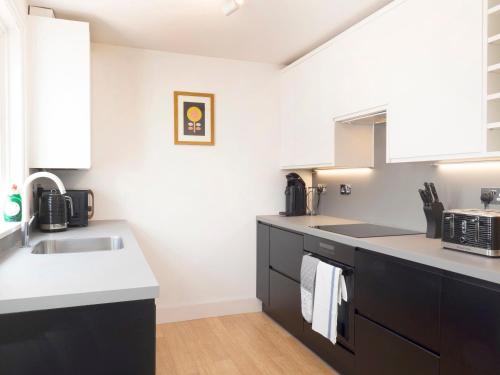 uma cozinha com armários pretos e um lavatório em Host & Stay - Herbert Road em Ramsgate