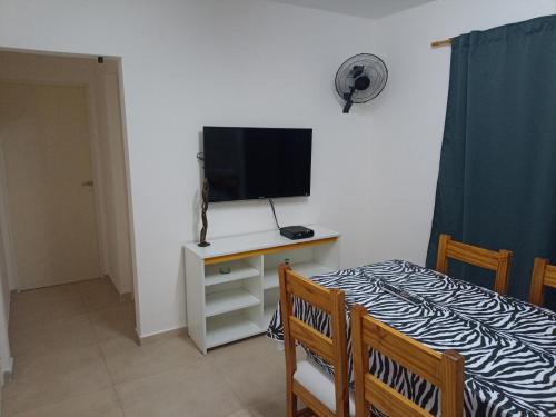 1 dormitorio con TV y mesa con cama en Departamento en primer piso en Venado Tuerto