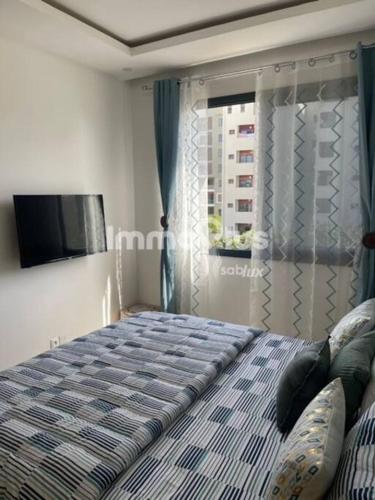 a bedroom with a bed with a television and a window at Eden Home Point E Studio Neuf in Dakar