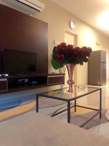 una sala de estar con un jarrón de rosas sobre una mesa de cristal en Dzora Vista Alam en Shah Alam